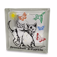 Un bloc de verre décoratif avec une inscription personnalisée "Freesbee & Gypsie" et deux silhouettes de chats noires. Le bloc est orné de papillons et d'un soleil colorés, et contient des guirlandes lumineuses LED chaudes et scintillantes.